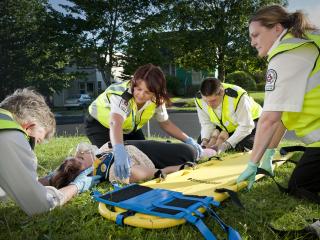 Group of SJA MFRs helping a patient lying on the ground.