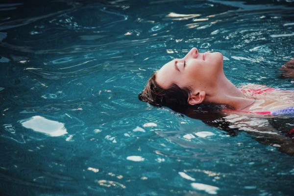 Woman floating on body of water. Photo by Haley Phelps on Unsplash