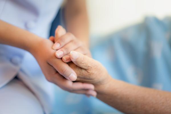 Care worker hand holding patient hand